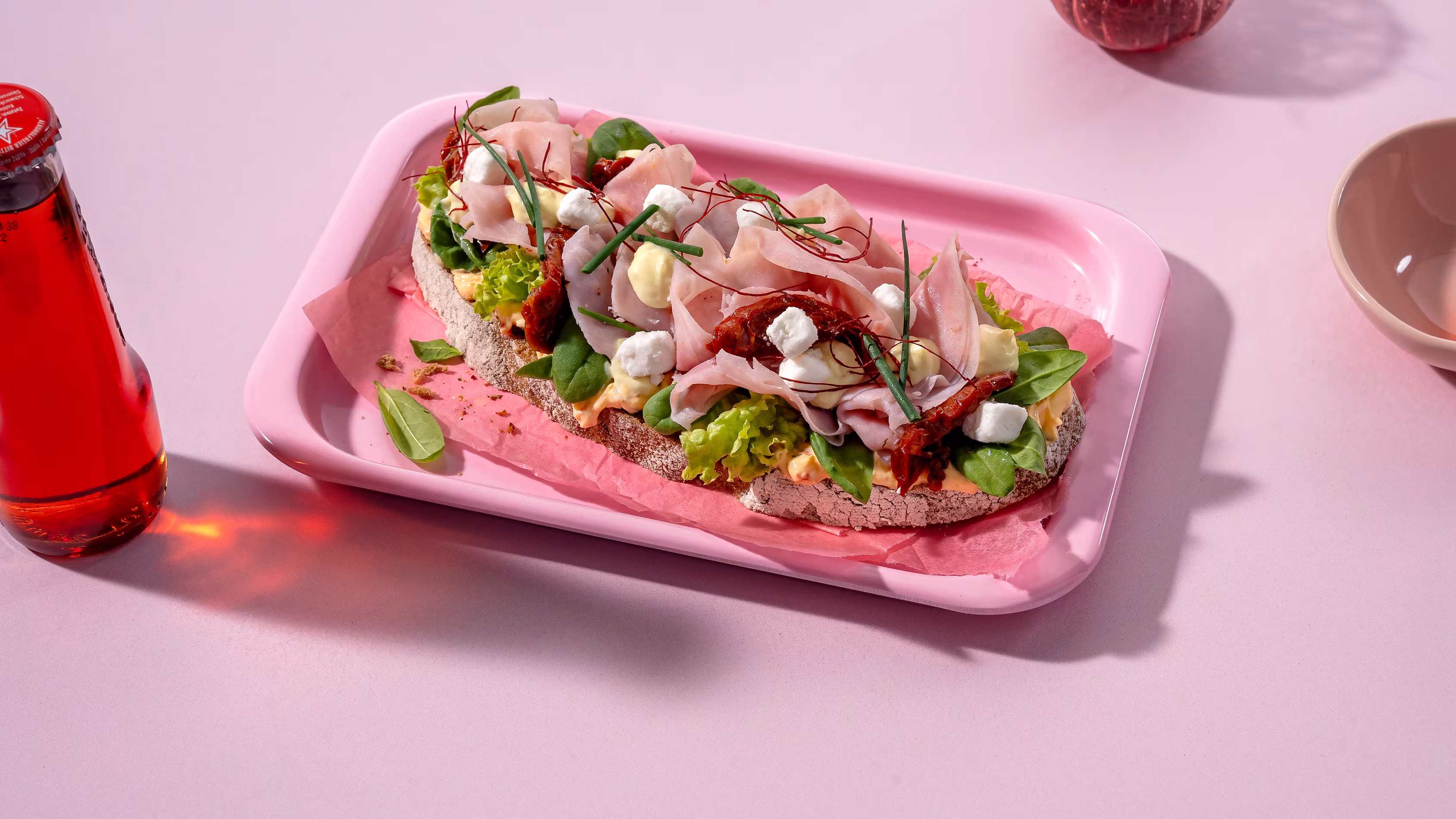 Belegtes Brot serviert auf Tablett und rosa Untergrund